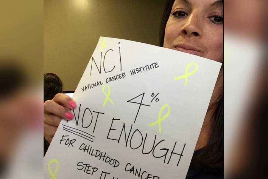 A woman holding up a sign that says nci national cancer institute.